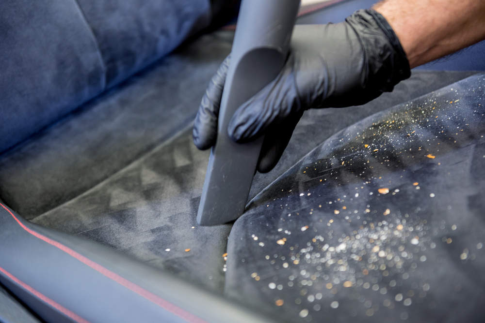 Vacuuming crumbs from a car seat during a Basic Interior detail